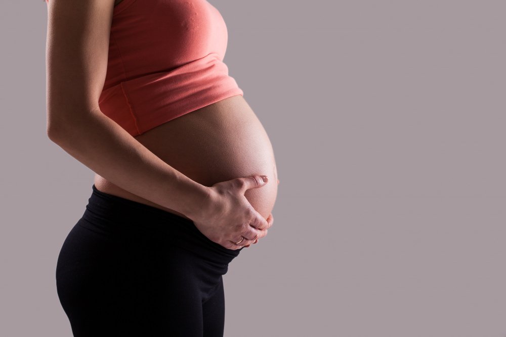 mulher grávida com as mãos na barriga